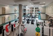 Optima Lakeview® Apartments in Chicago, IL Spacious gym with various exercise machines, weights, mirrors, and bright lighting. Multiple workout areas are visible.